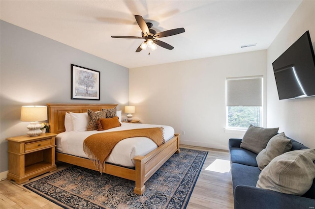 bedroom with baseboards, ceiling fan, visible vents, and wood finished floors