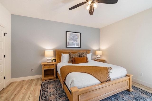 bedroom featuring a ceiling fan, light wood-style flooring, and baseboards