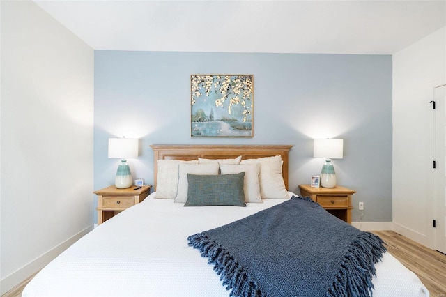 bedroom featuring light wood finished floors and baseboards