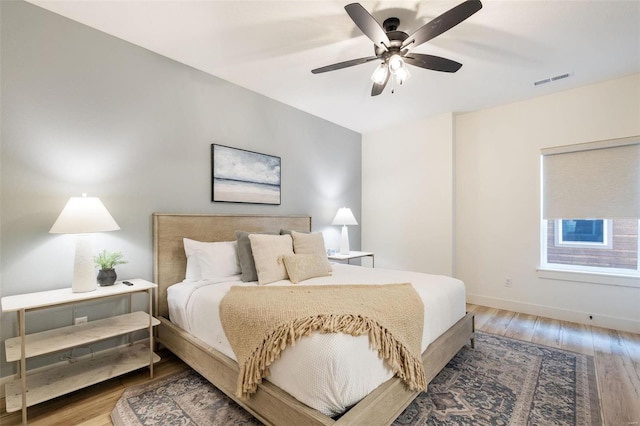 bedroom with a ceiling fan, baseboards, visible vents, and wood finished floors