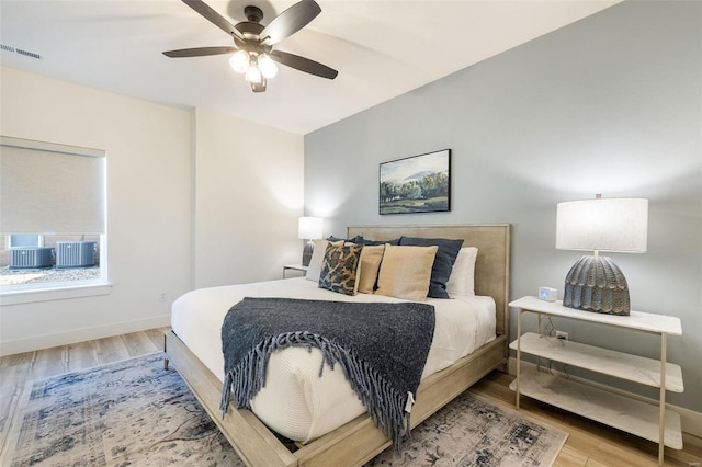 bedroom with wood finished floors, visible vents, and baseboards