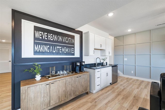 interior space with visible vents, light wood-style flooring, dark countertops, and white cabinetry