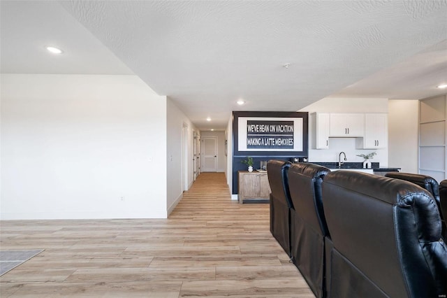 living area with baseboards, a textured ceiling, and light wood-style floors