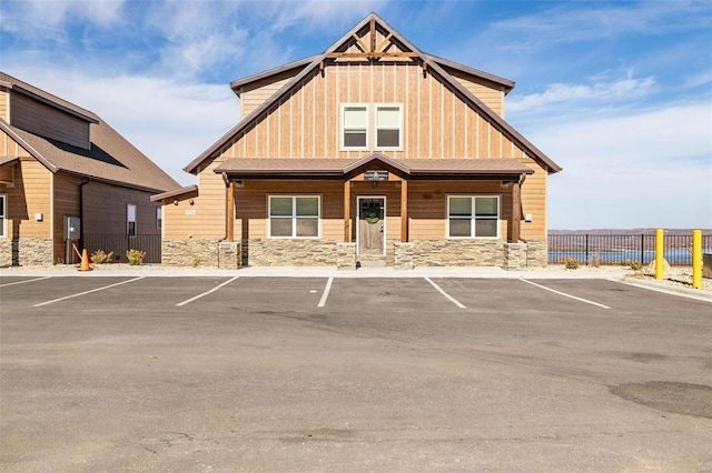 view of front facade featuring board and batten siding, stone siding, and fence