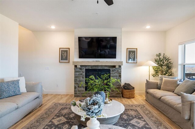 living area with light wood-type flooring, recessed lighting, a fireplace, and baseboards