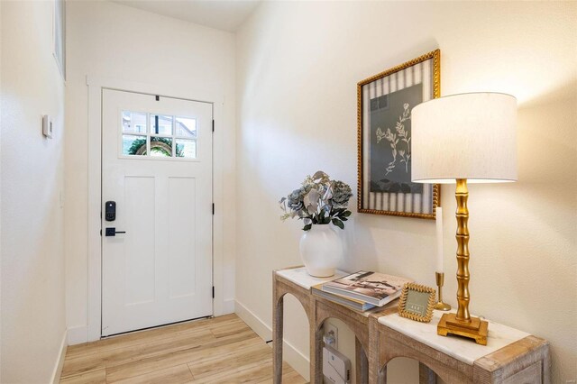 foyer entrance with light wood-style flooring and baseboards