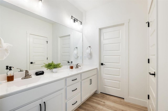 full bathroom with double vanity, a sink, and wood finished floors