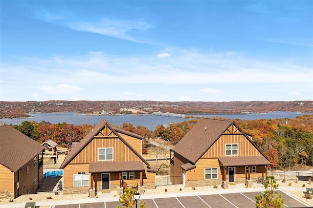 view of front of property with uncovered parking, stone siding, board and batten siding, and a water view