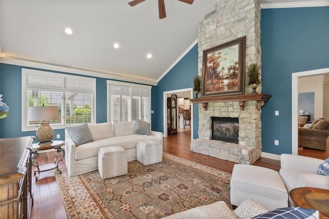 living room with a stone fireplace, dark hardwood / wood-style floors, ceiling fan, and ornamental molding