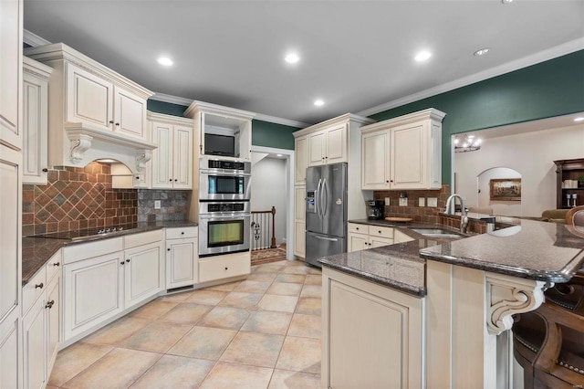 kitchen with stainless steel appliances, backsplash, dark stone countertops, sink, and kitchen peninsula