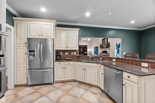 kitchen featuring an inviting chandelier, appliances with stainless steel finishes, tasteful backsplash, dark stone countertops, and sink