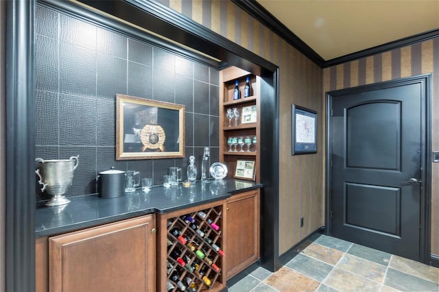 bar featuring backsplash, ornamental molding, and dark tile floors