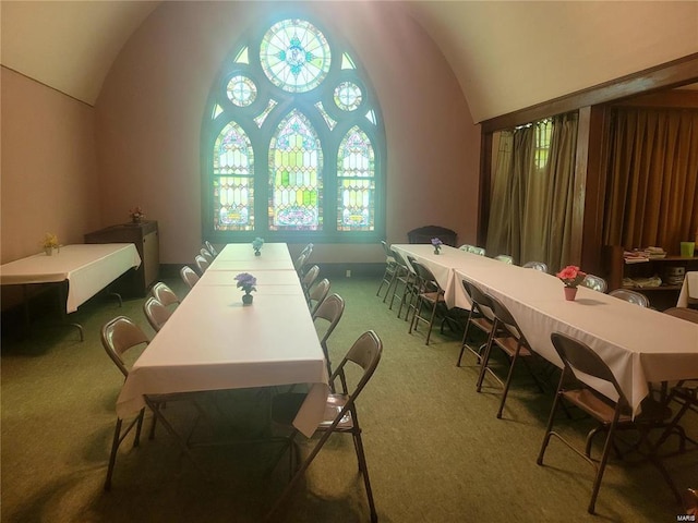 dining room with dark colored carpet and vaulted ceiling