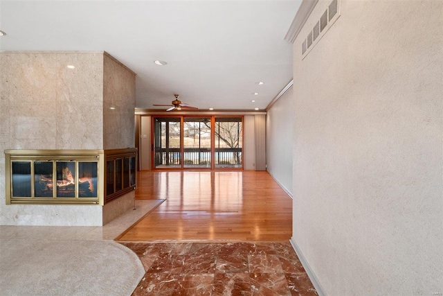 unfurnished living room with a multi sided fireplace, ceiling fan, and ornamental molding