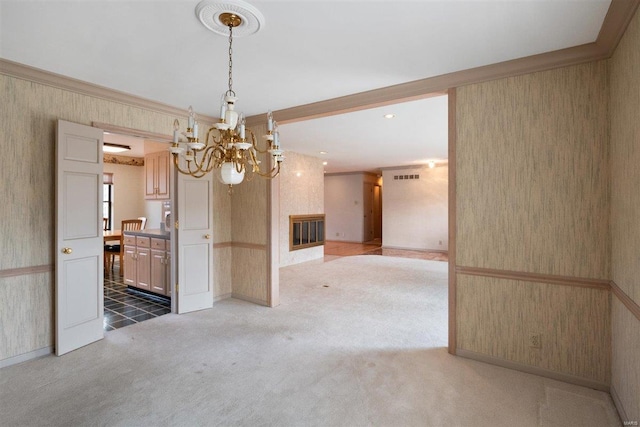 unfurnished dining area with a notable chandelier, a large fireplace, crown molding, and carpet floors