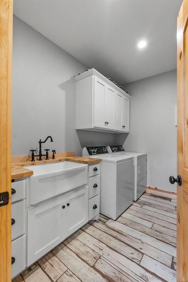 laundry room featuring cabinets, light wood-type flooring, washer and dryer, and sink