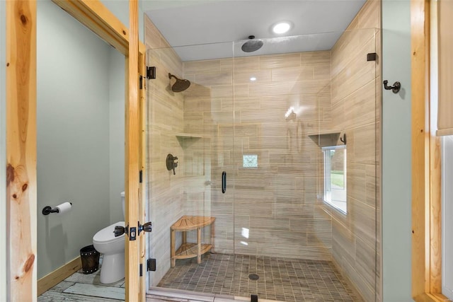 bathroom featuring a shower with shower door and toilet