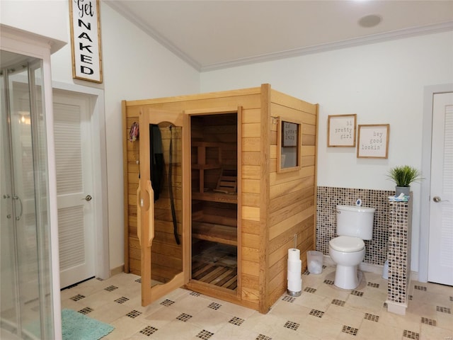 bathroom with toilet, ornamental molding, tile floors, and tile walls