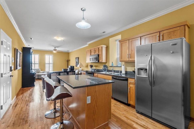 kitchen with ceiling fan, a breakfast bar, appliances with stainless steel finishes, light hardwood / wood-style flooring, and a center island