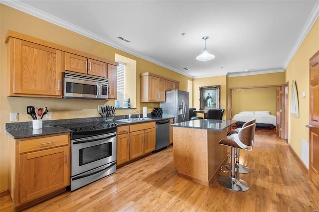 kitchen featuring hanging light fixtures, light hardwood / wood-style floors, stainless steel appliances, a kitchen bar, and a center island