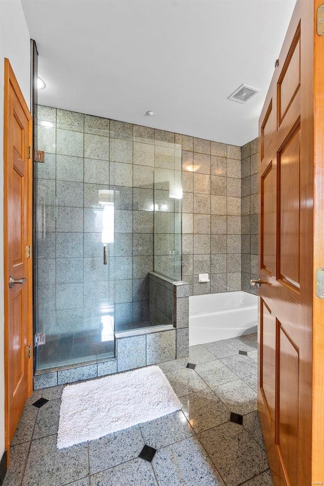 bathroom with tile walls, independent shower and bath, and tile flooring