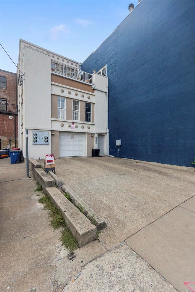 view of side of property featuring a balcony and a garage