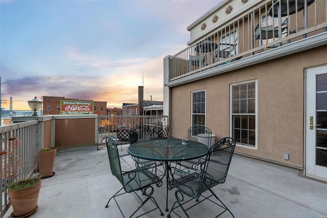 patio terrace at dusk featuring a balcony