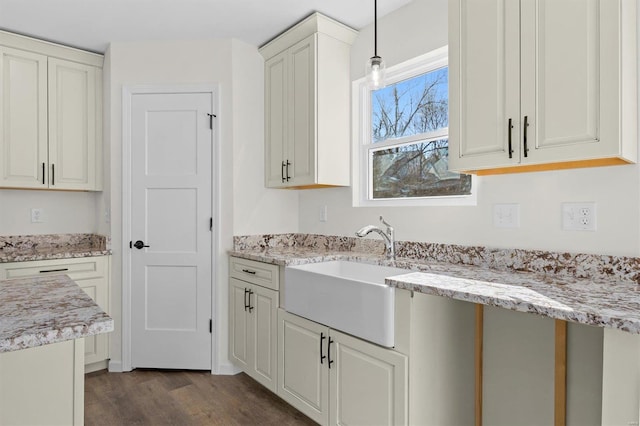 kitchen with light stone counters, dark wood-type flooring, sink, and pendant lighting