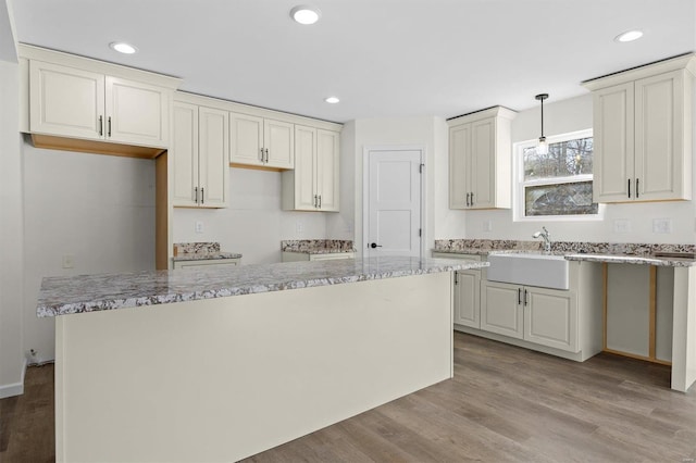 kitchen featuring sink, light hardwood / wood-style floors, decorative light fixtures, and white cabinetry