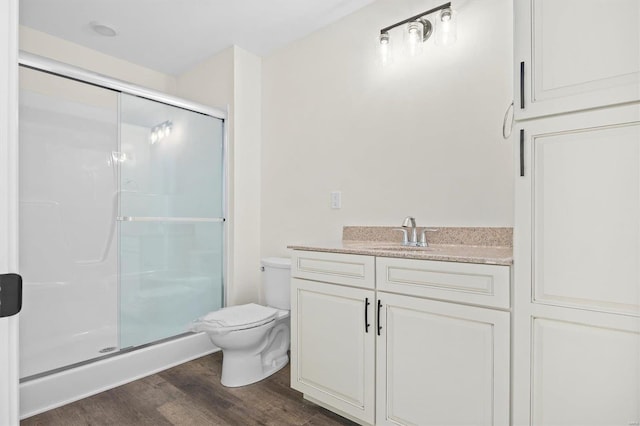 bathroom featuring walk in shower, hardwood / wood-style flooring, toilet, and vanity