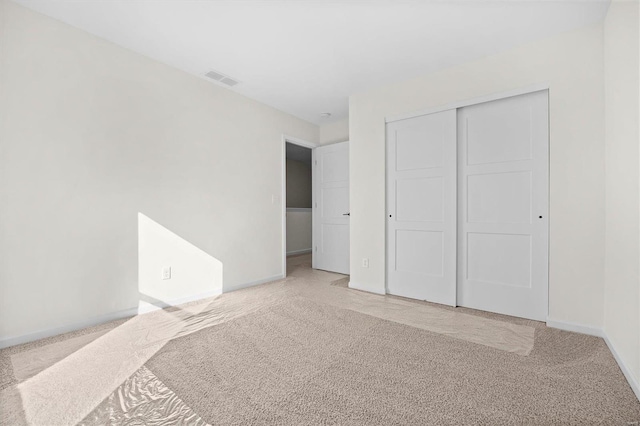 unfurnished bedroom featuring light carpet and a closet