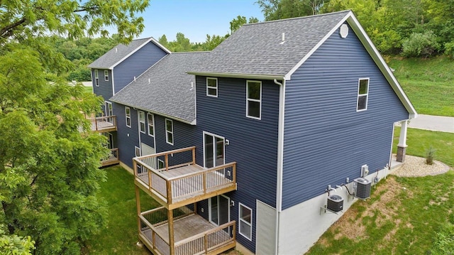 back of property with a wooden deck, central AC unit, and a lawn