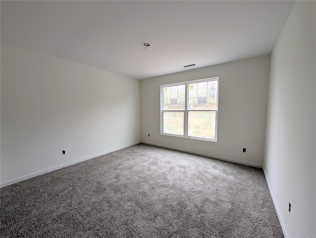 empty room featuring visible vents, baseboards, and carpet