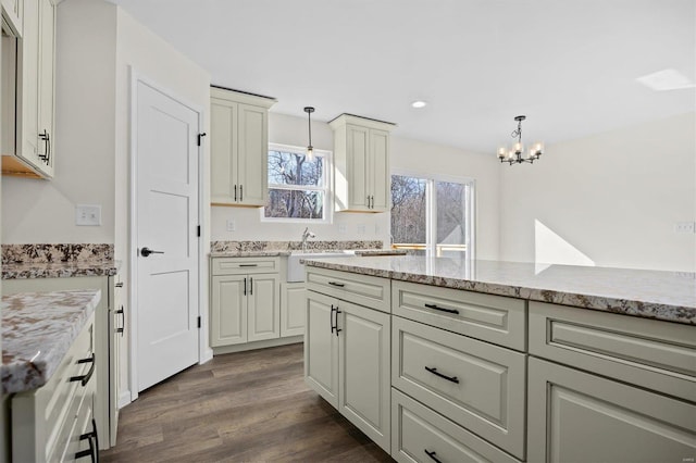 kitchen with dark wood-type flooring, white cabinets, light stone counters, and pendant lighting