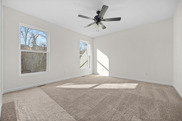 carpeted empty room with visible vents, baseboards, and a ceiling fan