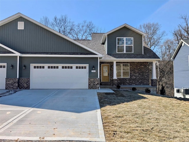 craftsman house with a front yard, an attached garage, covered porch, concrete driveway, and brick siding