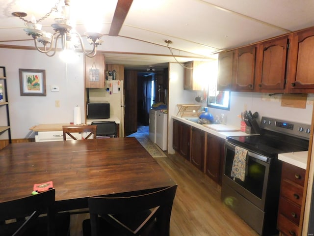 kitchen featuring an inviting chandelier, independent washer and dryer, stainless steel range with electric stovetop, and light hardwood / wood-style flooring