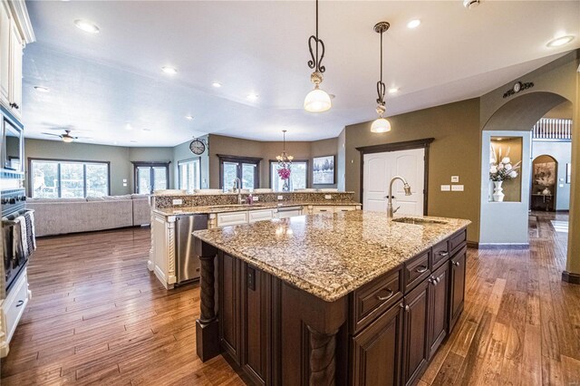 kitchen featuring decorative light fixtures, hardwood / wood-style floors, a kitchen island with sink, dishwasher, and sink