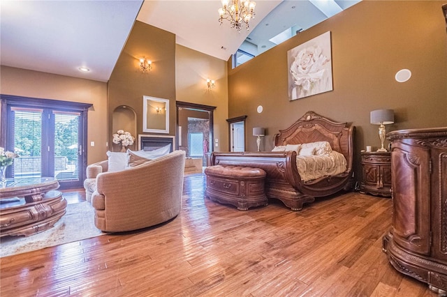 bedroom featuring high vaulted ceiling, an inviting chandelier, and light hardwood / wood-style floors