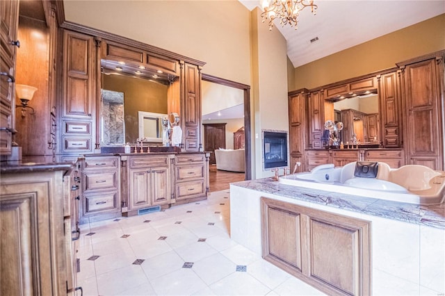 bathroom featuring an inviting chandelier, tile floors, a bath to relax in, vanity, and high vaulted ceiling