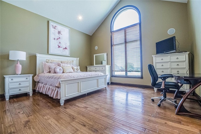 bedroom featuring high vaulted ceiling, multiple windows, and light hardwood / wood-style flooring