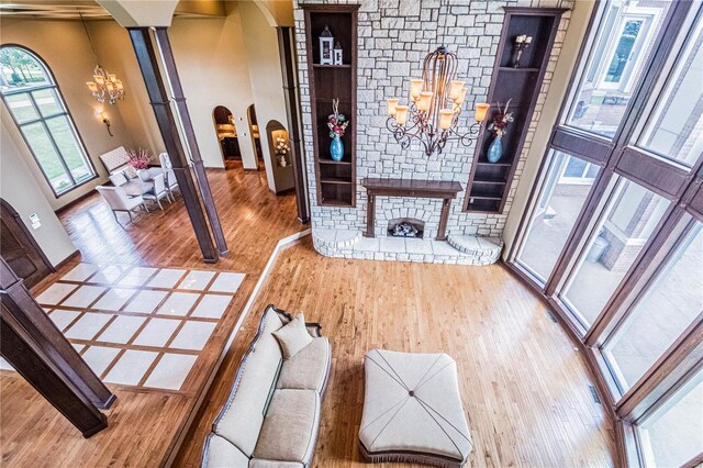 foyer entrance with a chandelier, brick wall, a stone fireplace, light hardwood / wood-style flooring, and a towering ceiling