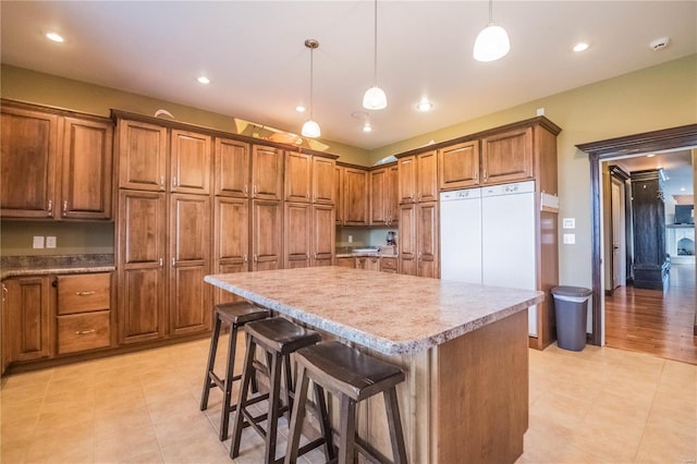 kitchen featuring light tile floors, a kitchen island, decorative light fixtures, and refrigerator