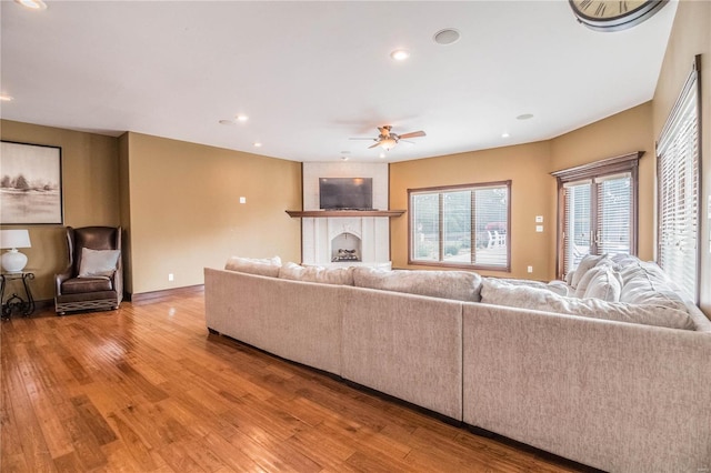 living room with ceiling fan, light wood-type flooring, and a fireplace