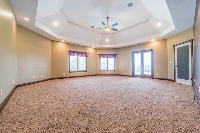 carpeted spare room with ceiling fan and a tray ceiling