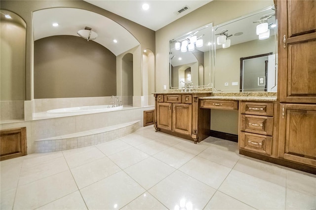 bathroom with tile floors, vanity, and tiled tub