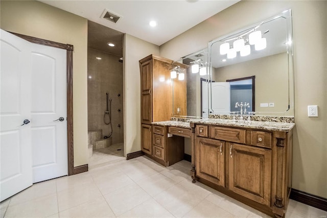 bathroom with tile floors, a tile shower, and vanity