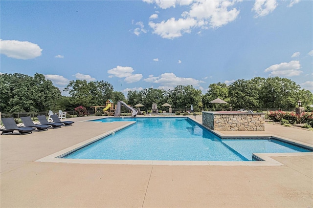 view of pool with a water slide and a patio