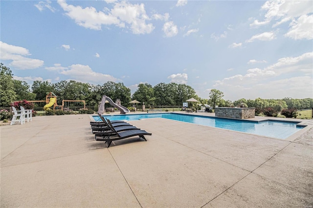 view of swimming pool featuring a water slide and a patio area