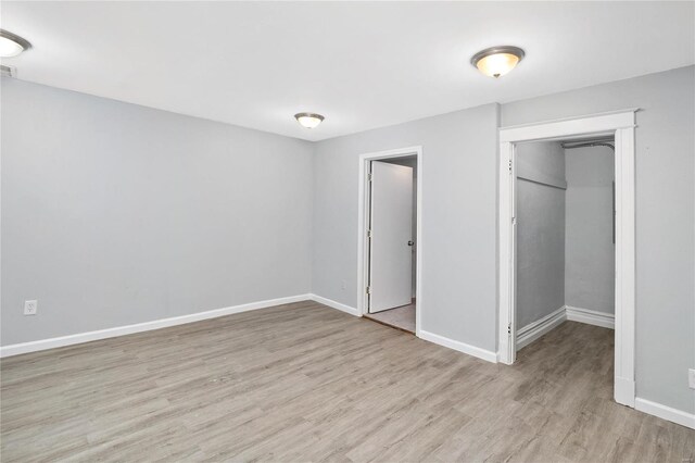 unfurnished bedroom with a spacious closet, light hardwood / wood-style floors, and a closet